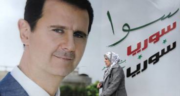 A Syrian woman walks past a placard bearing a portrait of President Bashar al-Assad in the city of Damascus on March 4, 2015. AFP PHOTO / LOUAI BESHARA